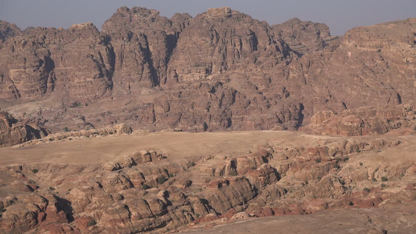 A jeep drives through epic mountains in the deserts of central Jordan in the Middle East