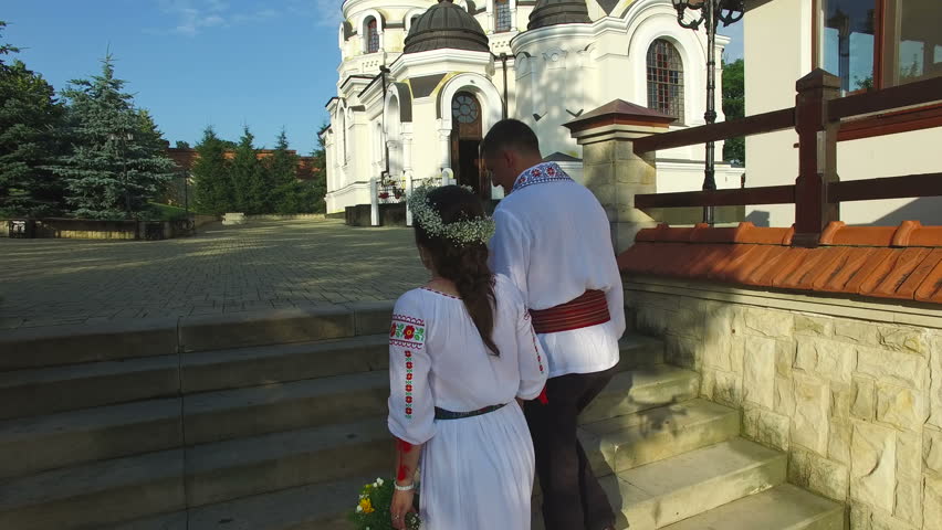 Aerial view of a beautiful couple walking up on stairs on wedding day. Happy newlyweds wearing traditional suits.
