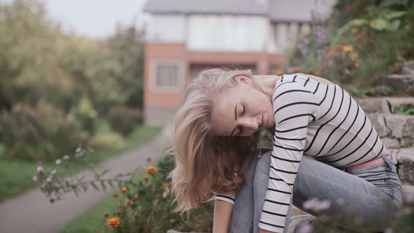 Young girl in the summer on the steps of the house around nature resting steps and smiling, stretches. Lifestyle casual