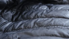 Close-up of tube wall filled jacket 4K 2160p 30fps UltraHD tilting footage - Slow tilt over synthetic surface of warm winter down parka 3840X2160 UHD video