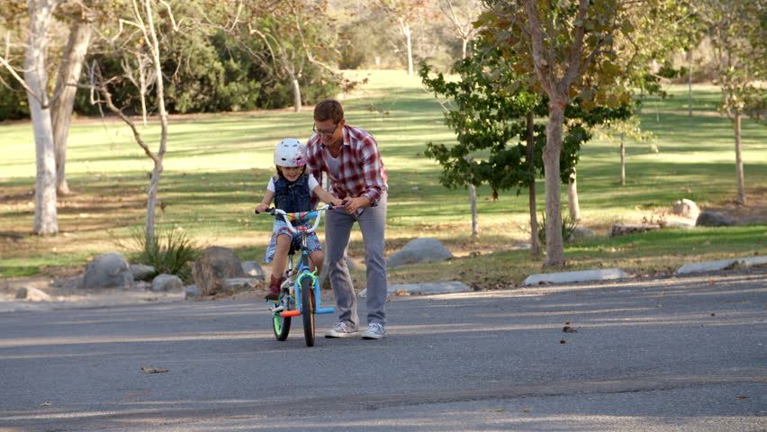 Father teaching his daughter to ride a bike in a park Royalty-Free Stock Footage #23120713