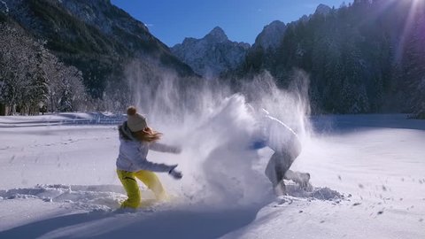 Slow motion - Man grabbing and tossing woman into the snow during a snowball fight