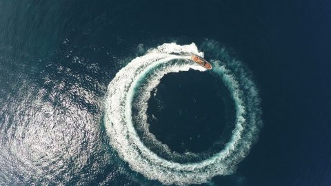 Perpendicular aerial view of a maxi rib designing a circle in the sea navigating fast
