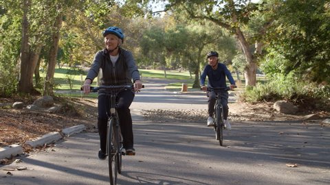 Senior Couple Cycling Through Park In Slow Motion