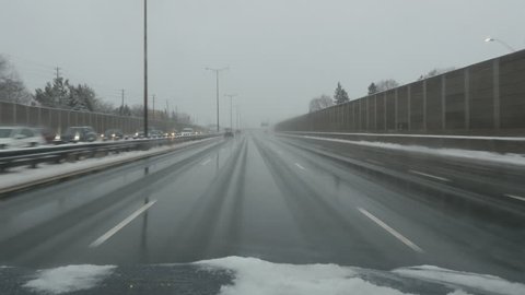 Driving on wet, winter highway. QEW going west. Toronto, Canada. No logos visible on vehicles or buildings. 
