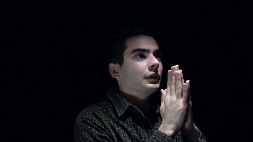Christian young man praying in the dark.