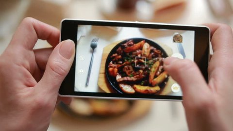 Trendy man in a restaurant make photo of food with mobile phone camera