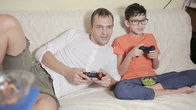 father and son play video game inside their house on the couch