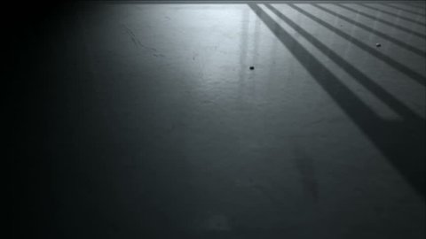 A 4K static camera closeup showing a dimly lit floor of a prison cell and the cast shadows of the door slamming shut