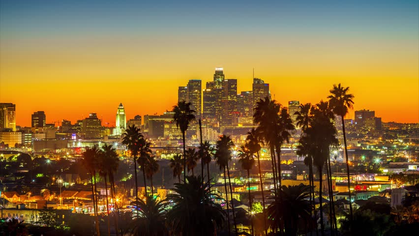 Twilight to night transition city of Los Angeles downtown skyline palm trees in foreground. 4K UHD timelapse.