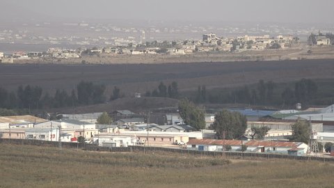 View of the Israel - Syria border and a United Nations disengagement force camp, with destroyed and collapsed buildings on the Syrian side
