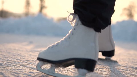 Low section of kid feet ice skating on frozen lake in sunny day