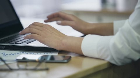Hands of female office employee typing on laptop, inserting data in e-document