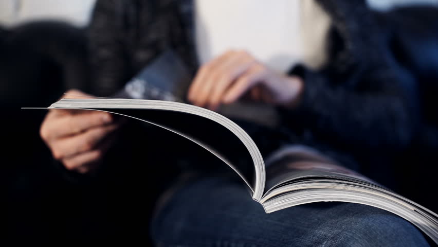 Casual man leafing through a glossy magazine. indoor, close up | Shutterstock HD Video #23155285
