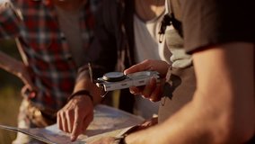 Bearded spectacled caucasian male holding map and compass surrounded by two friends trying to find way. Close up view in slowmotion - Powered by Shutterstock - Get 15% off with code: PIKWIZARD15