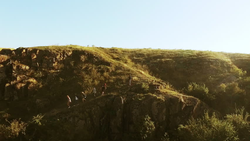 Tourists going down rocky trail in prairie. Panoramic flyover view in slowmotion
