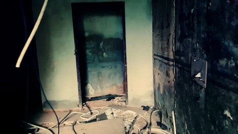 Camera moves along hall and turns left to dark corridor with light in end. Exploring empty building destroyed by earthquake. Interior of abandoned house, post-apocalyptic ruins. Live cam view.