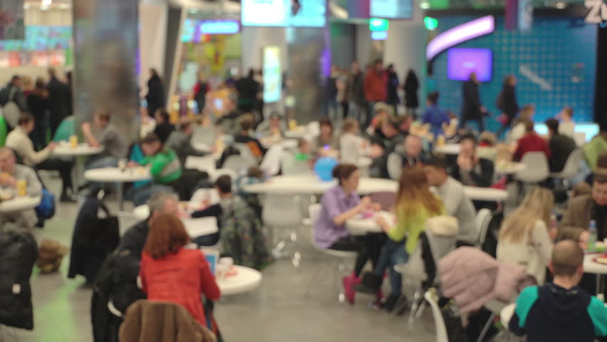 Concept junk food. Unrecognizable people eating fast food in mall food court