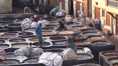FEZ, MOROCCO - DECEMBER 2016: Men dye leather skin in a traditional tannery in Fez, Morocco
