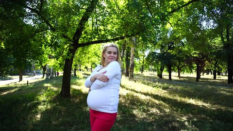 Beautiful Young Pregnant Feminine of European Appearance Decided to go Outside and Get Some Fresh Air, Tired of Household Chores and Yawns in Green Sunny Park Outdoors in Daytime. Female With Blonde