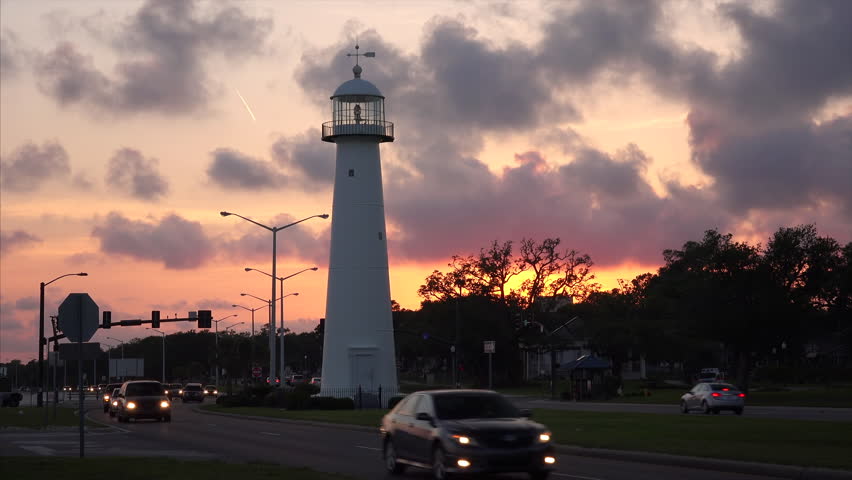 Lighthouse at sunset as cars drive past in Biloxi, Mississippi