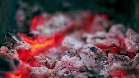 Flicker of smoldering coals lay in cinder, closeup view