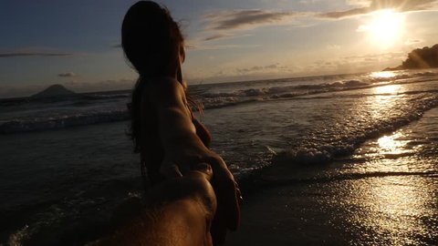 Back view of a couple having fun and holding hands on the beach - Slow Motion
