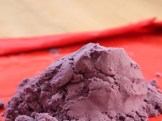 Purple kinetic sand falls Close-up.