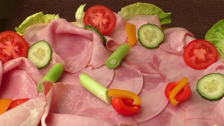 Food tray with delicious salami, pieces of sliced ham, tomatoes, salad and vegetable - Meat platter with selection
