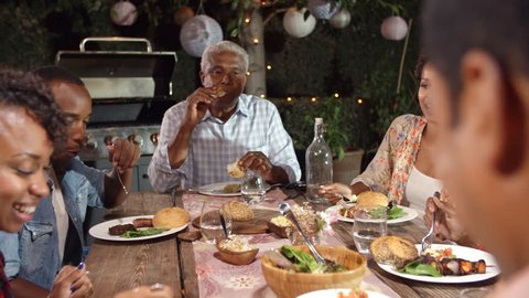 Adult black family eating outside at a dinner table