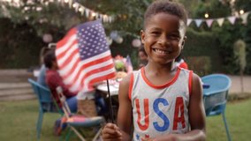 Young black boy waving US flag at 4th July family barbecue - Powered by Shutterstock - Get 15% off with code: PIKWIZARD15