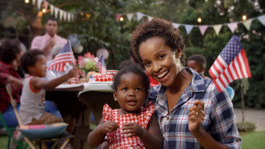 Black mother and baby girl wave flag at 4th July party Royalty-Free Stock Footage #23190076
