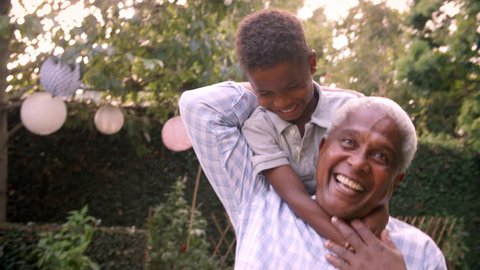 Young black boy playing with grandad in the garden, close up
