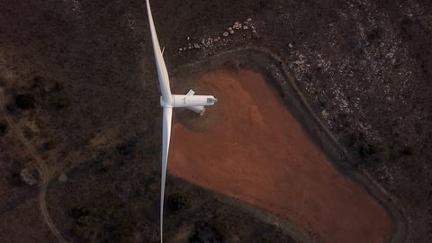 Aerial drone shot of single wind turbine spinning, clean energy renewable resource