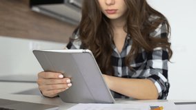 Young casual girl using digital tablet for work or for study at home 