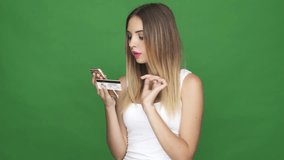 Thoughtful young woman using credit card and using smartphone isolated on a green background