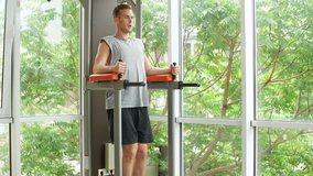Young athlete man doing press exercises using gym equipment indoors