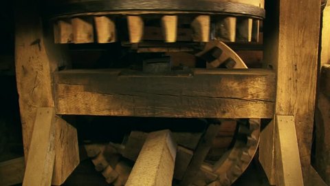 Cogwheels rotate in a 90-degree angle in an industrial corn mill. Sound of creaking and groaning of the timber
