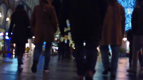 Ground level steadicam shot of blurred touristic street in the evening. Popular destination with stores and cafes. 4K background bokeh video