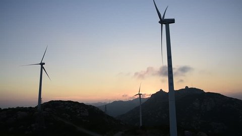 The mountain wind turbines in the sunrise and sunset