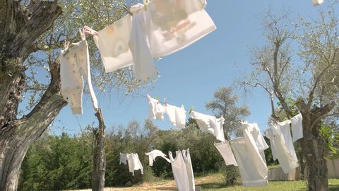 White clothes hanging on rope. Trees and blue sky. Use hypoallergenic washing powder.