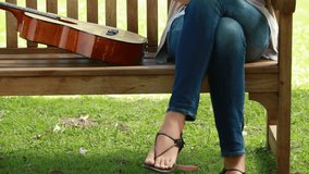 Woman reading a book with a guitar next to her on a bench - Powered by Shutterstock - Get 15% off with code: PIKWIZARD15
