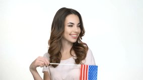 Smiling casual woman holding USA flag and pointing finger at camera isolated on a white background