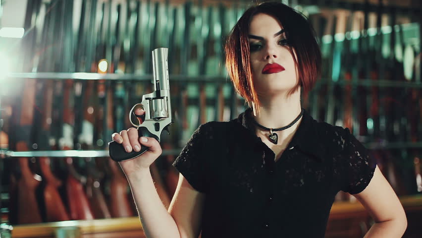 Attractive woman aims a gun.