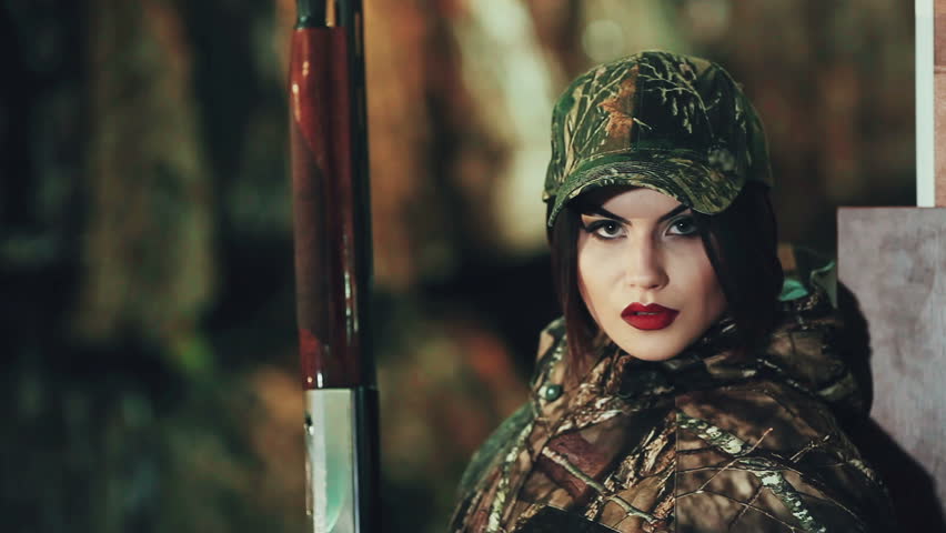 Girl in a military uniform and with a pump-action shotgun. posing on camera.
