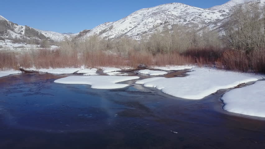 Aerial winter mountain river pond ice snow. Beautiful winter scenic landscape. Snow covered mountain and valley, river stream by trees. National Scenic Byway on Nebo Loop in Wasatch Mountains.