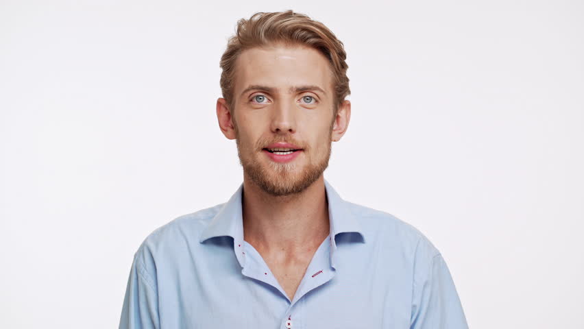 Young Caucasian male with blue eyes and brown beard standing on white background in amazement