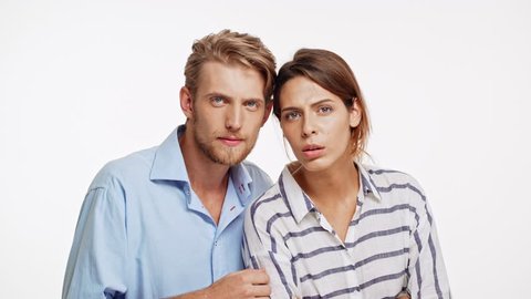 Young Caucasian pair looking at camera with suspicion on white background