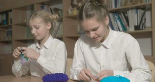 Two girls learn to knit in the classroom or room