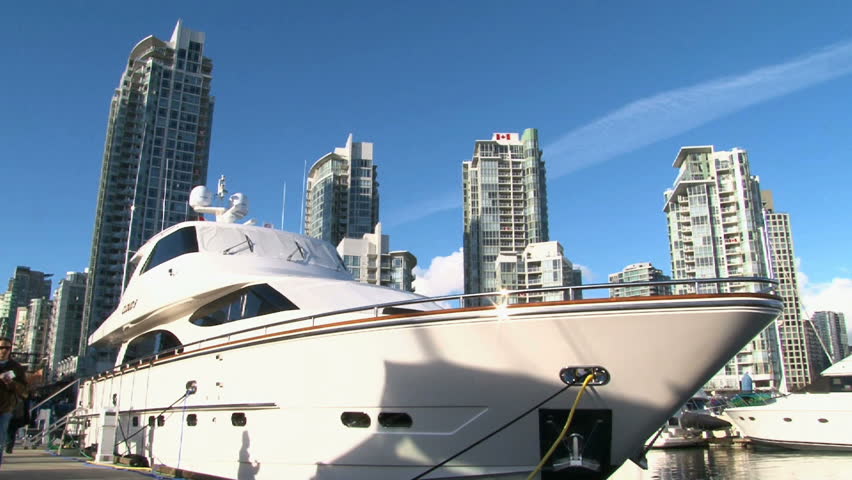 Elderly couple walk past large yacht in the Yaletown Marina around Vancouver,